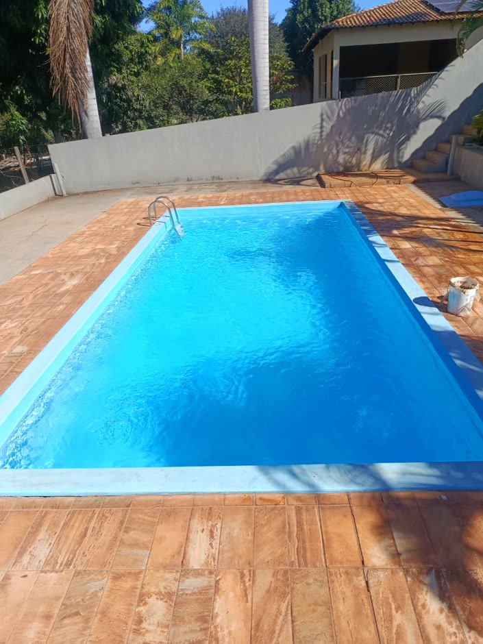Depois: a mesma piscina com a água azul e limpa, deck de cerâmica e muro ao fundo